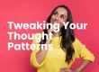 Woman in a yellow knitted top with long brown hair, smiling looking up to her right side. With a thoughtful gesture by holding her right hand to her face. Letters in white writing - Tweaking your thought patterns.